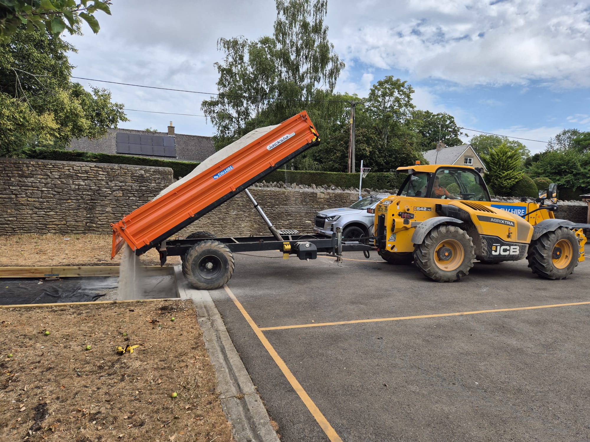 JCB 542-70 tipping sand into a pit with a dropside trailer